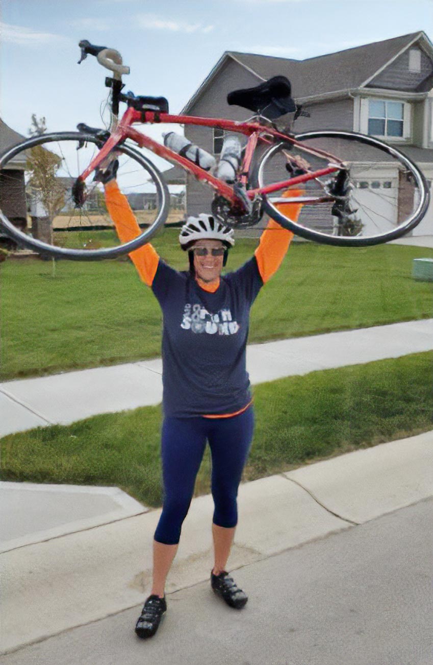 Deborah Gravel holding bike above her head