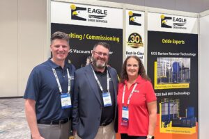 Three people in front of an EAGLE exhibit booth at BCI 2025