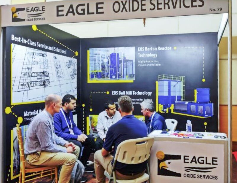 group of people talking in a EAGLE Oxide Services exhibit booth
