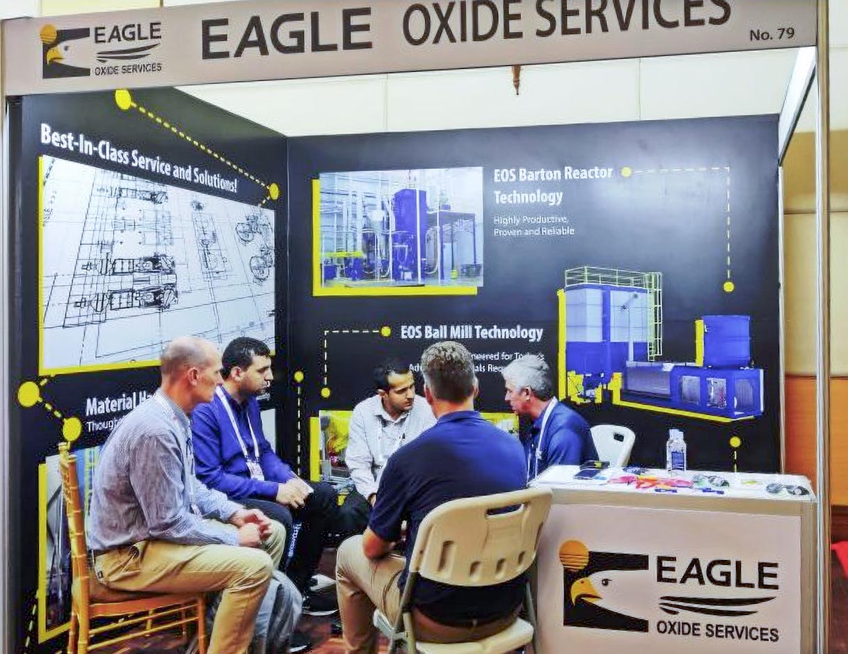 group of people talking in a EAGLE Oxide Services exhibit booth