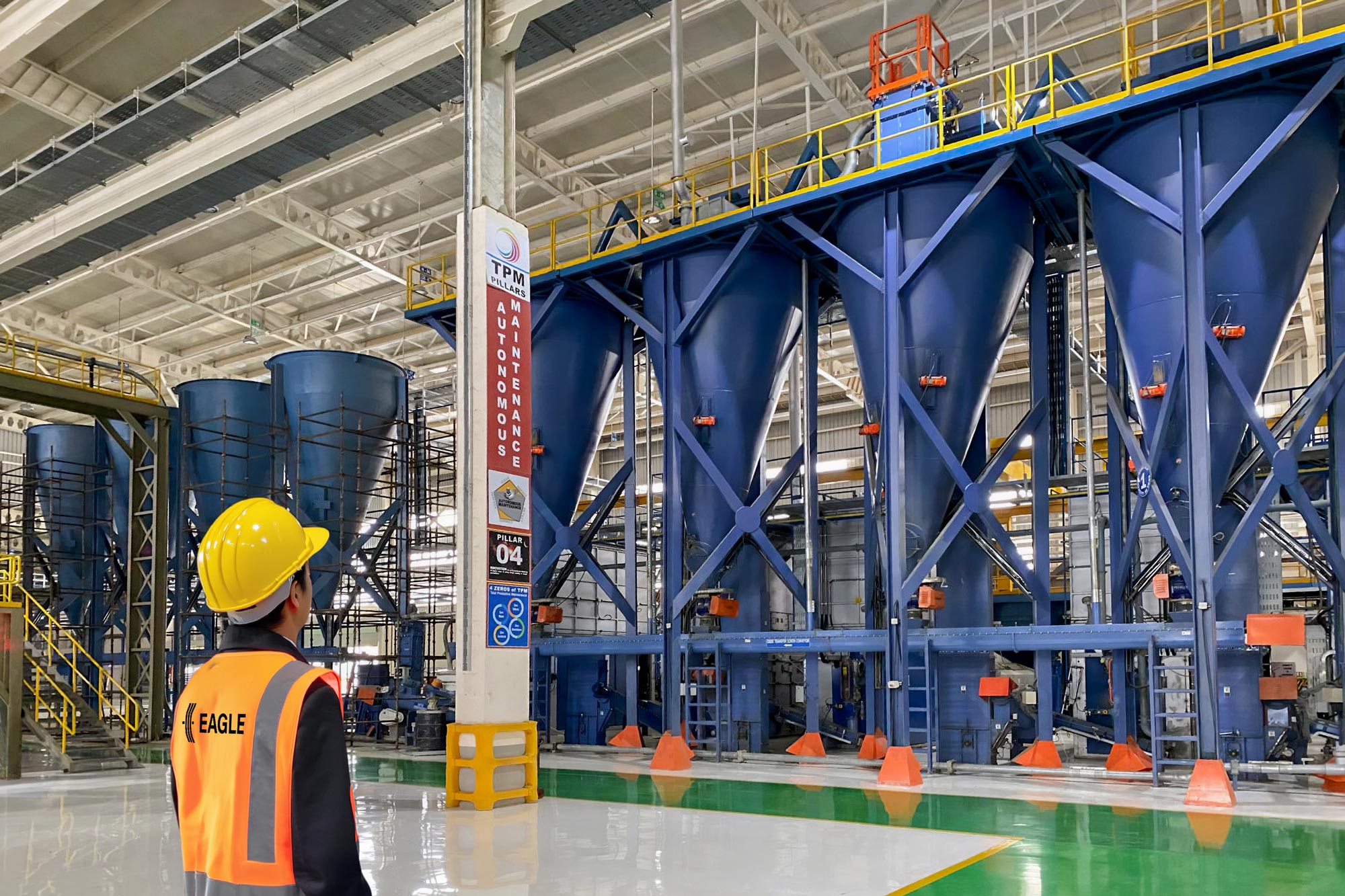 factory worker in hard hat looking at large silos