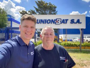 two men in Eagle branded shirts in front of a Union BAT S.A. factory