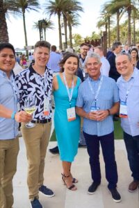 Group of people smiling for a photo with palm trees in the background