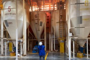 person in hard hat looking up at large silos