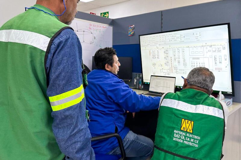 Three people commissioning services looking at machinery schematics on a computer screen