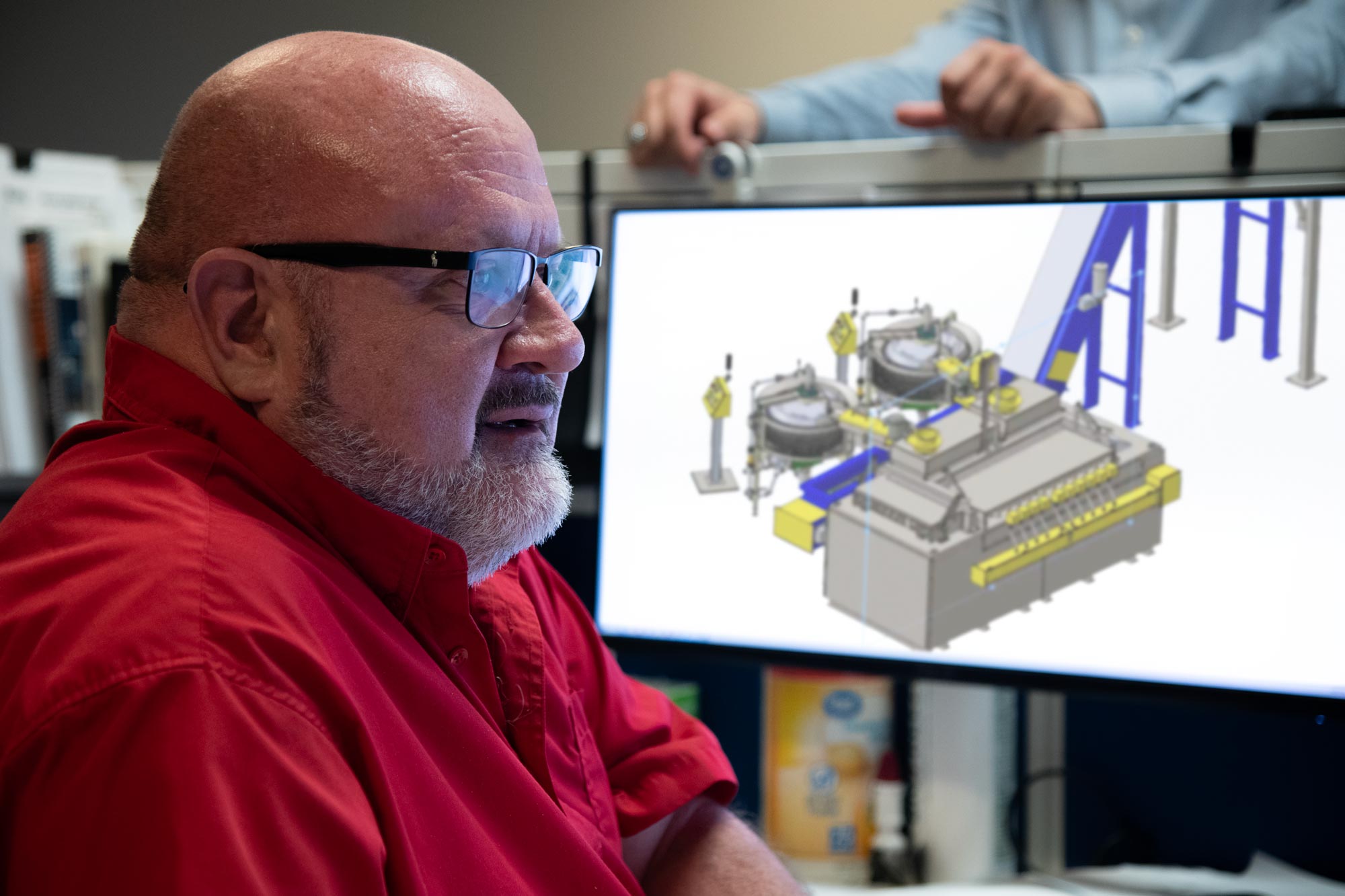 Engineer at a computer with machinery renderings, cylinder caster