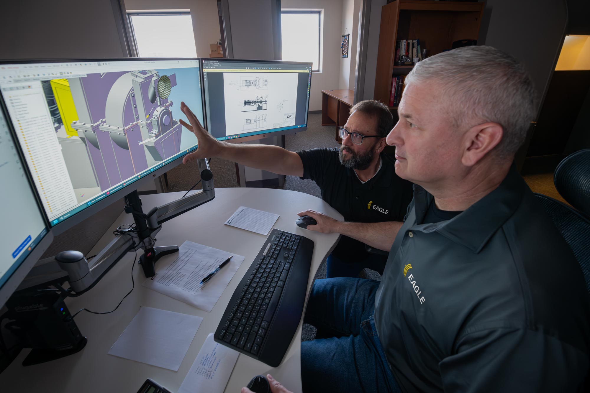 two engineers looking at machine renderings on a computer screen